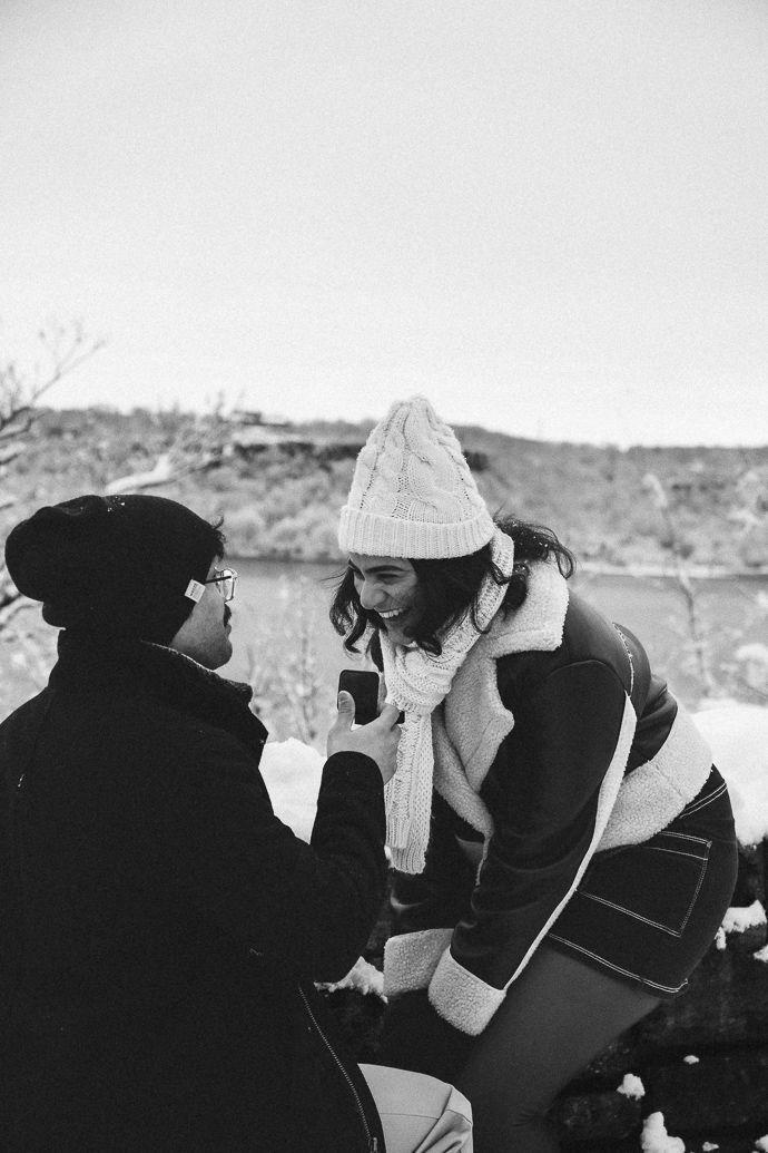 A couple laughs together on a cobblestone street in DUMBO.